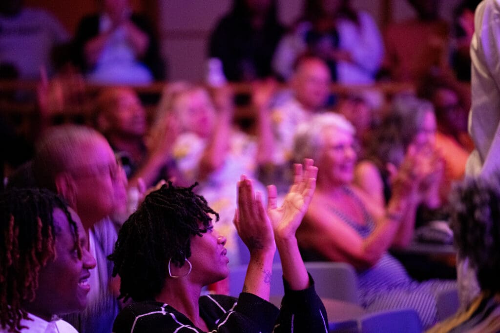 Person raising hands to clap at a performance.