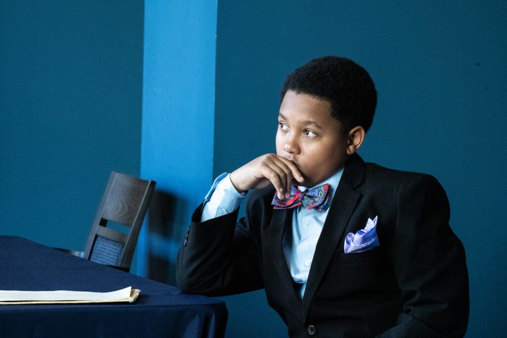 Child in a suit sitting at a table.